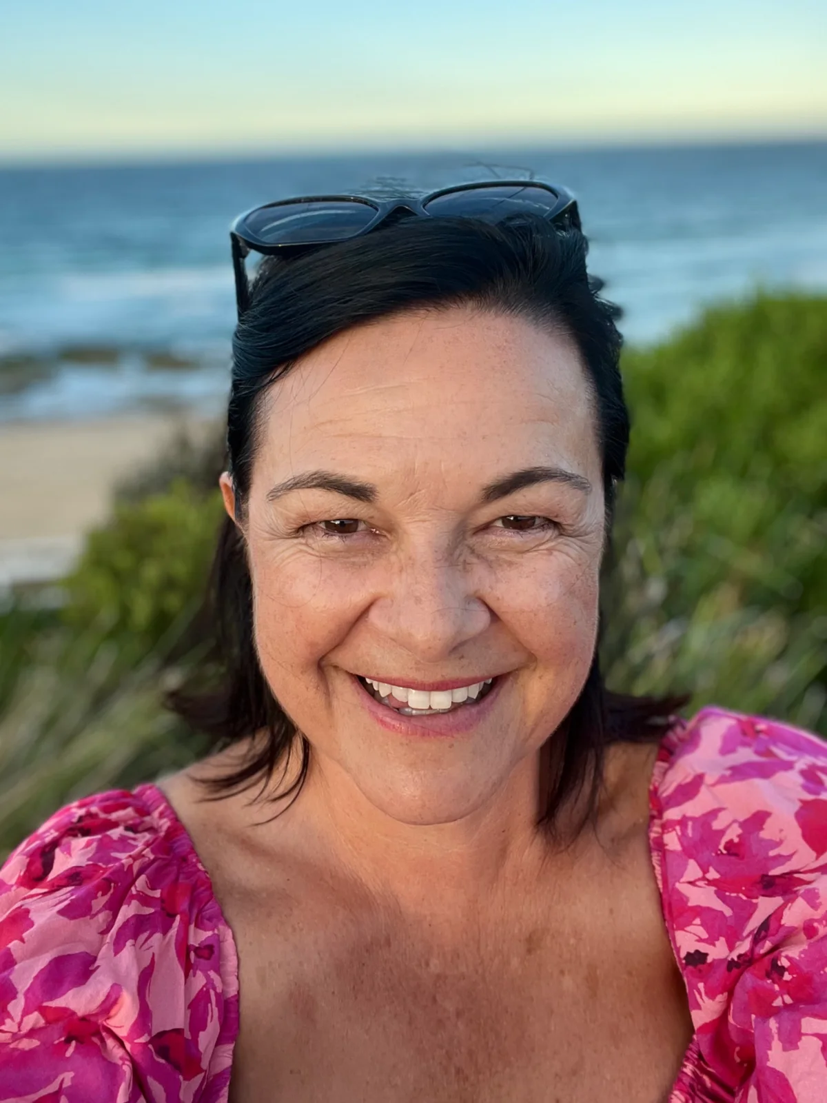 Angela smiling by the coast.