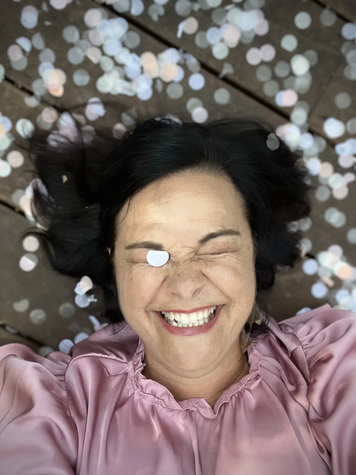 Angela laughing as she lies in confetti.
