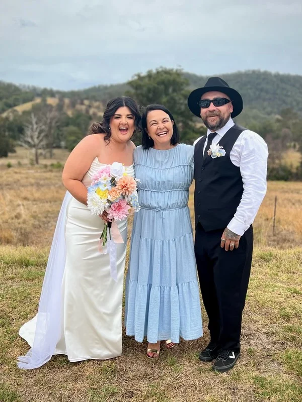 Angela with a newly married couple in rural grassland.