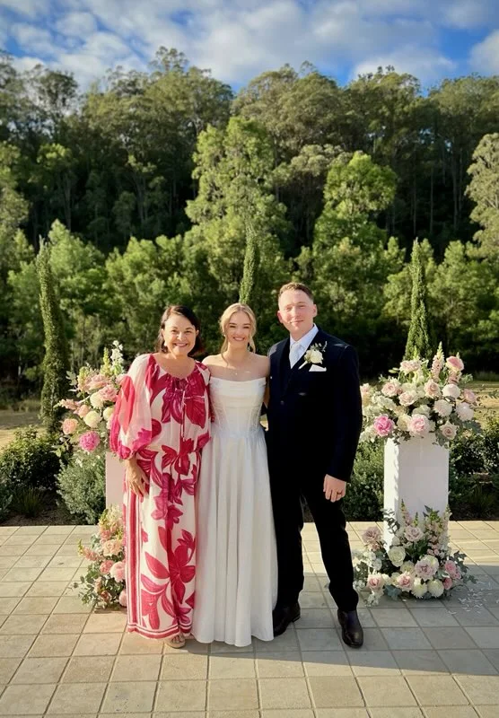 Angela with a newly married couple in a garden.
