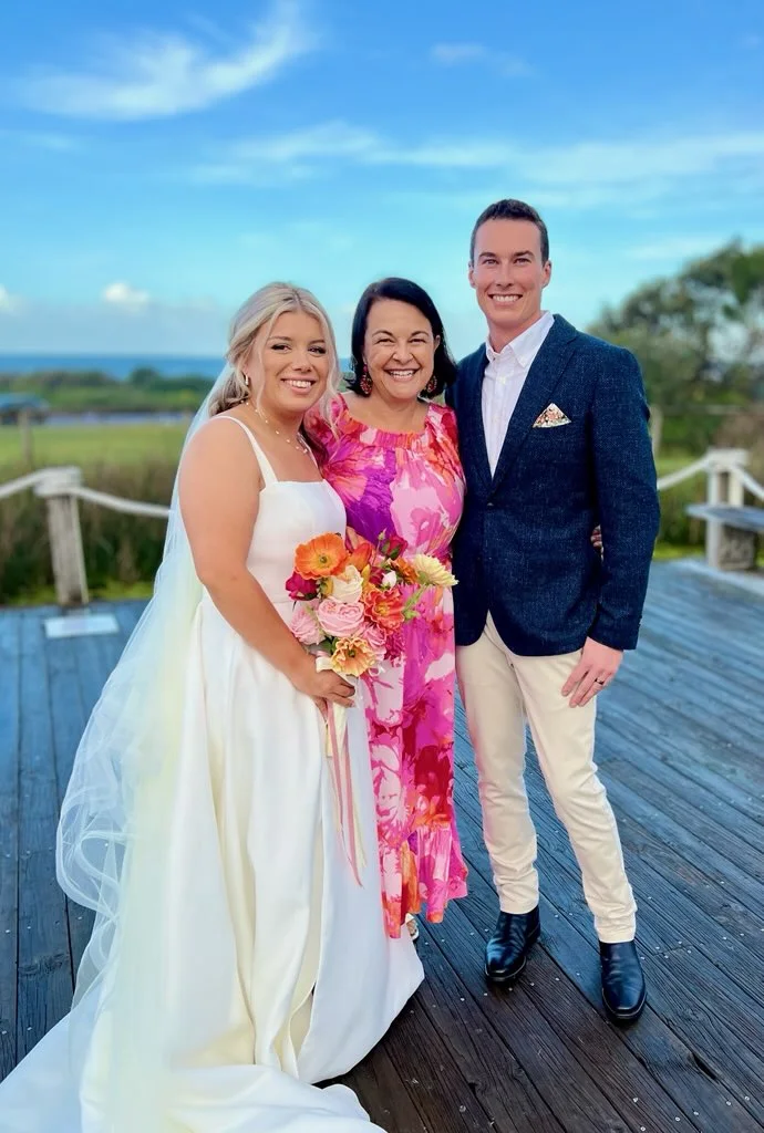 Angela with a couple on a coastal boardwalk.