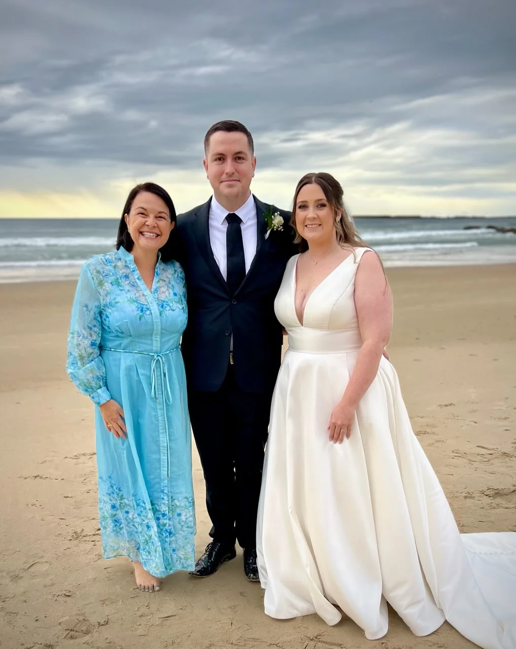 Angela in blue with a wedding couple on the beach.