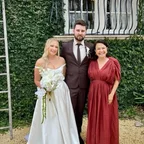 Angela with a wedding couple outside an ivy-covered building.