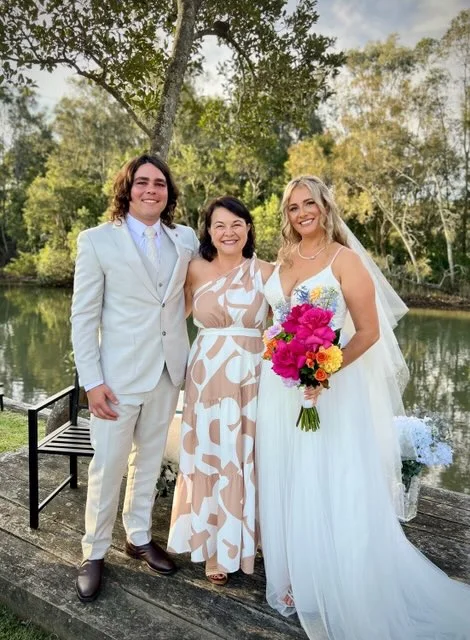 Angela with a newly married couple beside a pond.