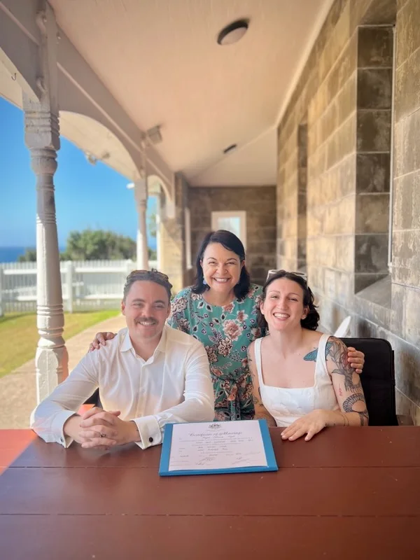Angela with a wedding couple at the signing table.