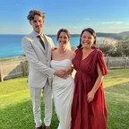 Angela with a wedding couple on a coastal lawn.