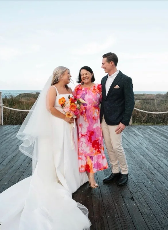 Angela with a wedding couple on a beach boardwalk.