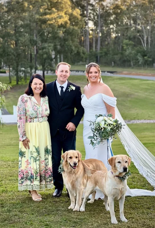 Angela with a wedding couple and their two golden retrievers.