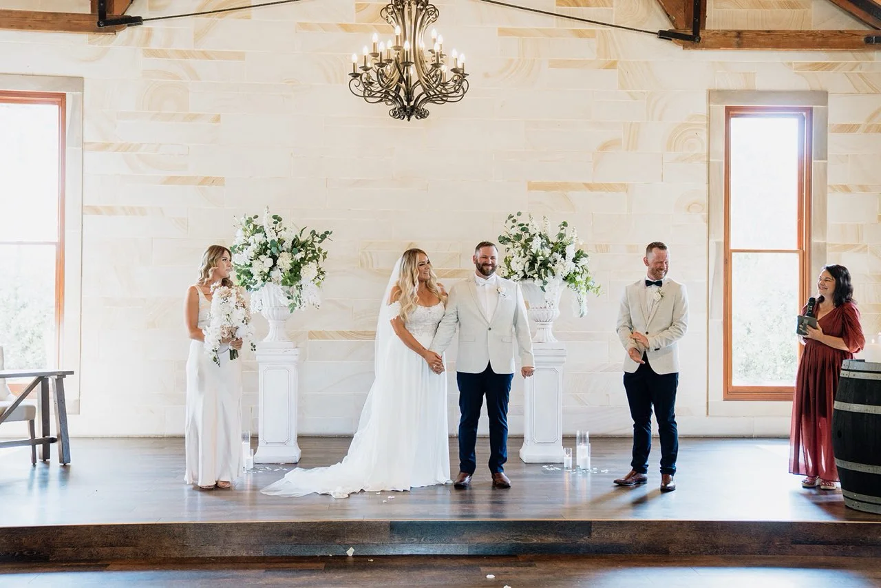 An indoor ceremony in a sandstone hall with a chandelier.