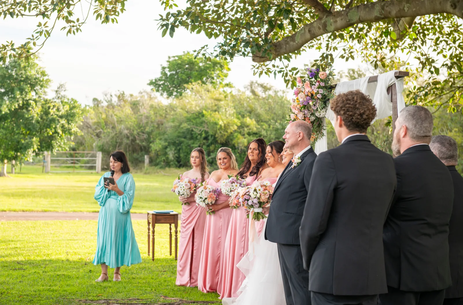 Angela leading a garden wedding with the couple and their wedding party.
