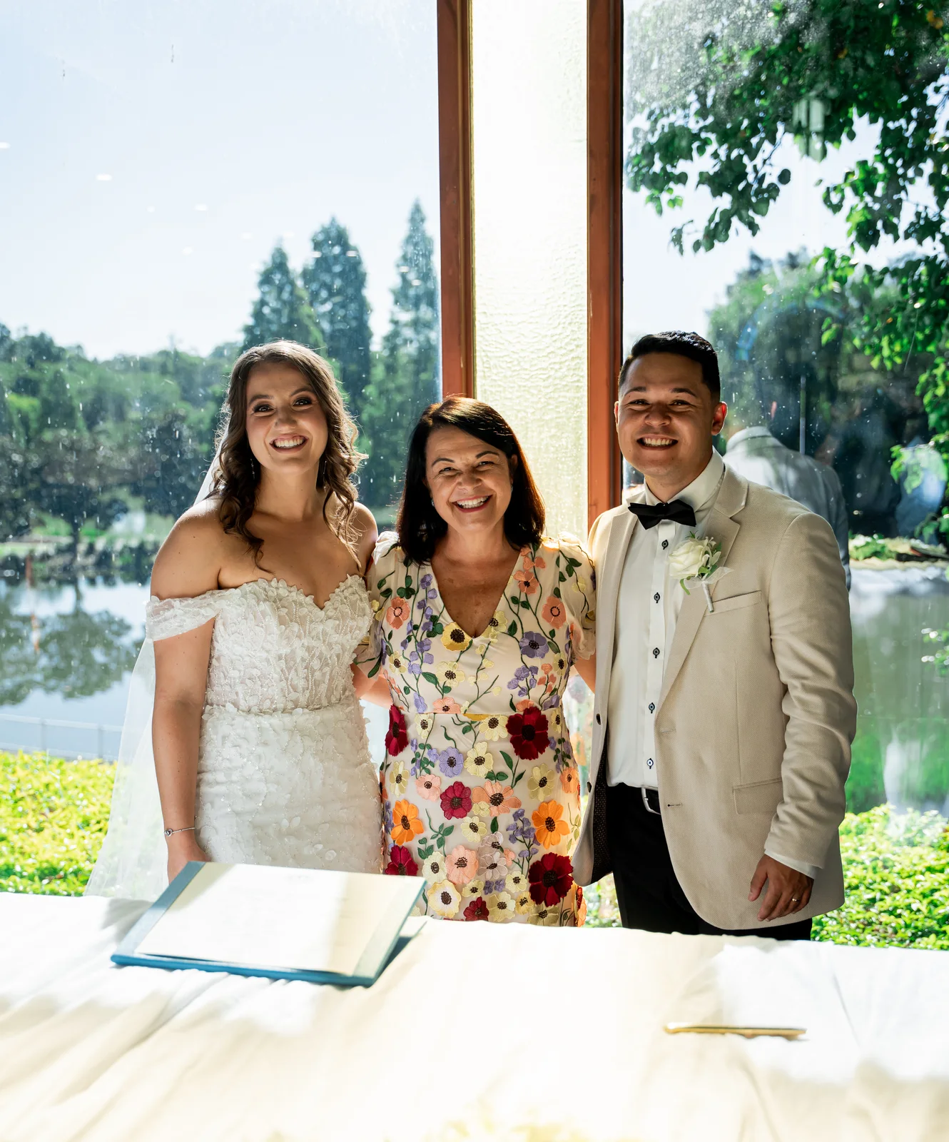 Angela smiling with a couple at their marriage signing table.