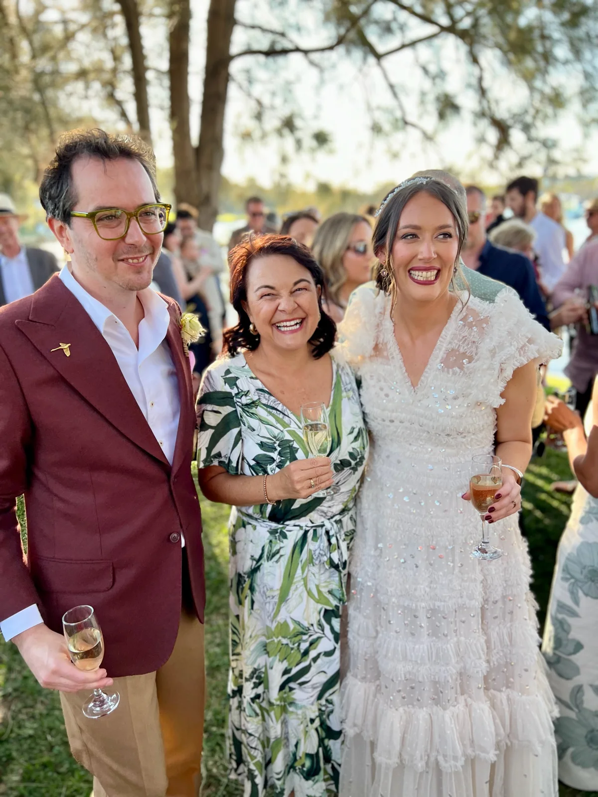 Angela with a newly married couple at an outdoor celebration.